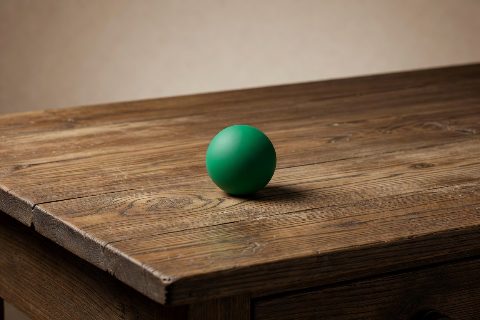a small green sphere on a wooden desk, studio photo